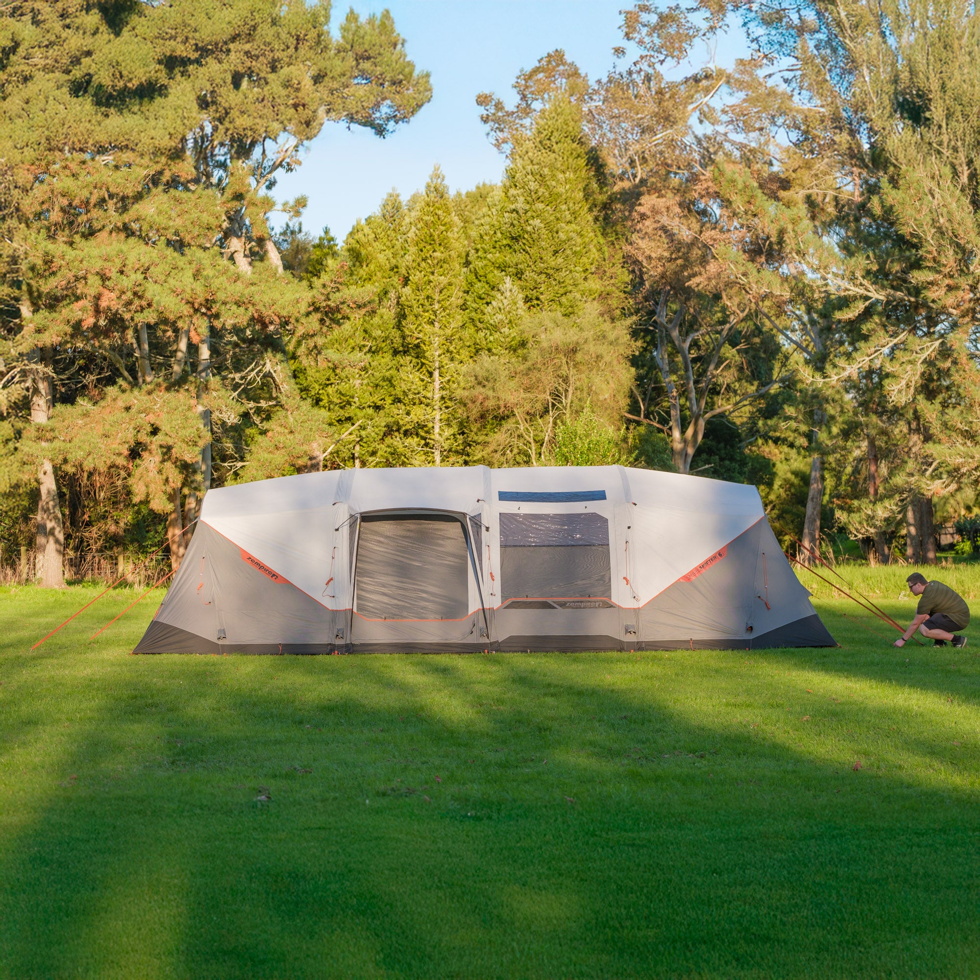 Large camping tent Zempire Shapeshifter SLAS set up in a grassy area with trees in the background
